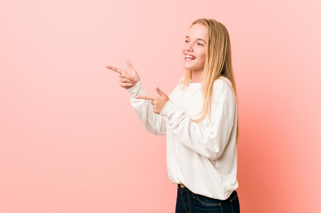 La giovane donna bionda dell'adolescente ha eccitato indicare con gli indici di distanza.