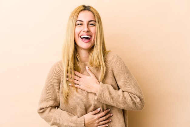 La giovane donna bionda ride allegramente e si diverte a tenere le mani sullo stomaco