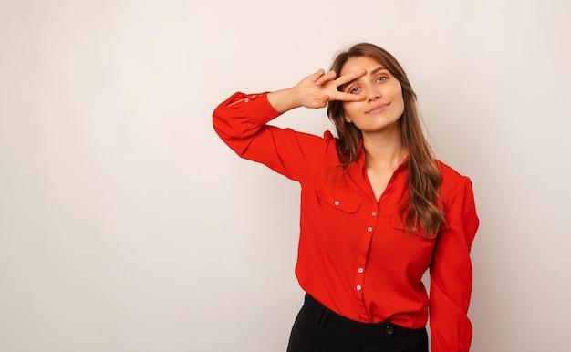 La giovane donna bionda sorridente bella sta tenendo il gesto v sopra il suo occhio