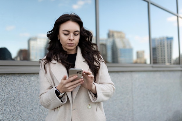 La giovane donna brunetta libera professionista comunica nei social network al telefono per strada