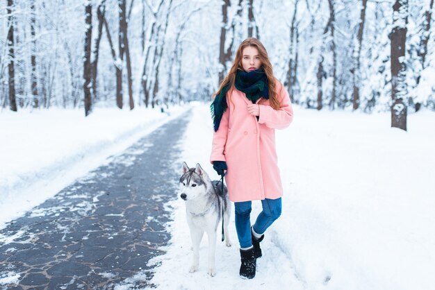 La giovane donna cammina nel parco con il husky siberiano