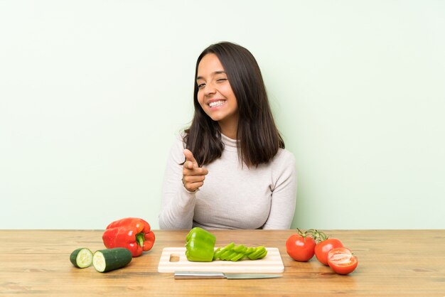 La giovane donna castana con le verdure indica il dito voi