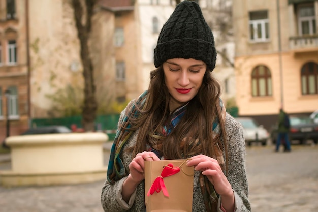 La giovane donna castana disimballa un regalo. Colpo di strada