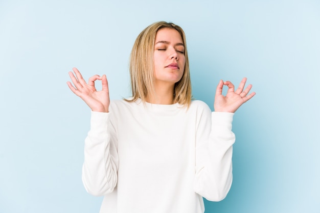 La giovane donna caucasica bionda isolata si rilassa dopo una dura giornata di lavoro, sta eseguendo lo yoga.