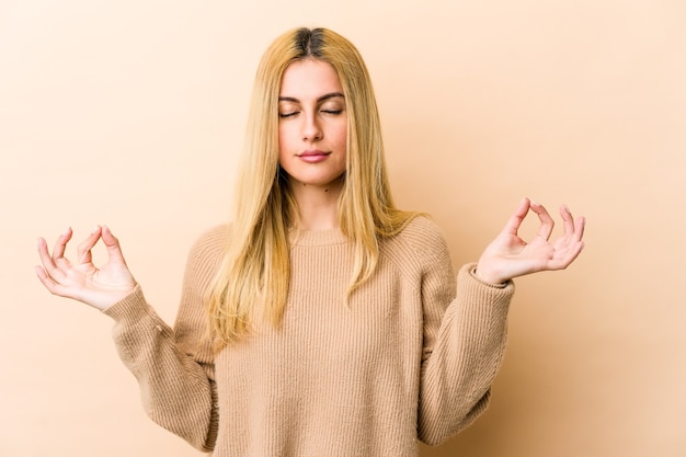 La giovane donna caucasica bionda si rilassa dopo una dura giornata di lavoro, sta eseguendo lo yoga.