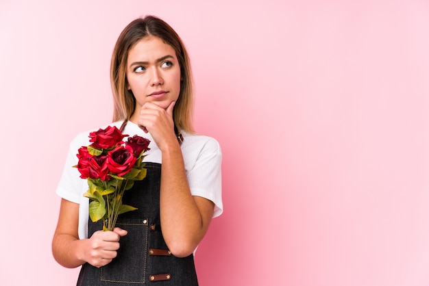 La giovane donna caucasica che giudica rose ha isolato lo sguardo lateralmente con l'espressione dubbiosa e scettica.