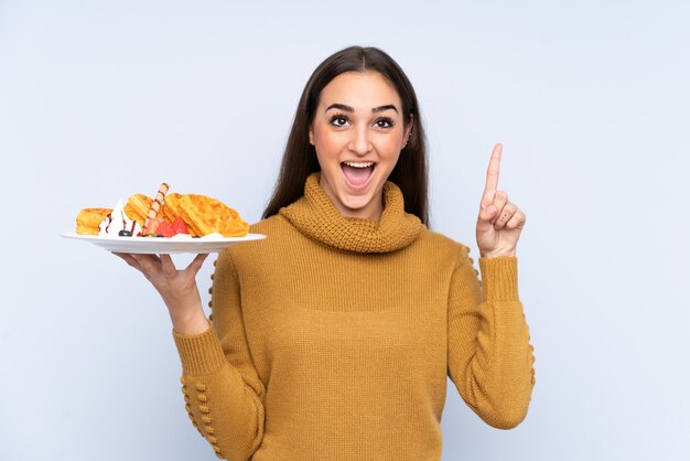 La giovane donna caucasica che tiene le cialde isolate che indica su una grande idea