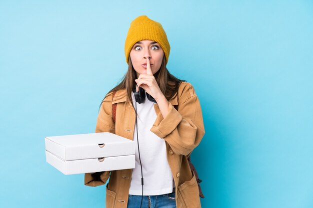 La giovane donna caucasica che tiene le pizze ha isolato mantenendo un segreto o chiedendo il silenzio.