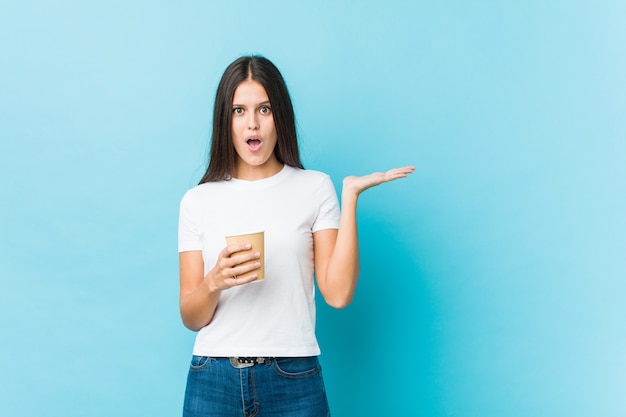 La giovane donna caucasica che tiene un caffè da asporto ha impressionato lo spazio della copia della tenuta sul palmo.