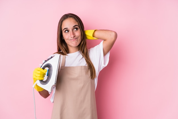 La giovane donna caucasica con il ferro da stiro ha isolato la parte posteriore commovente della testa, pensando e facendo una scelta.