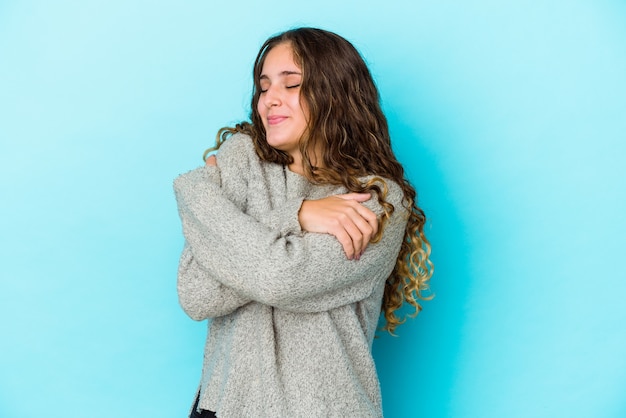 La giovane donna caucasica dei capelli ricci ha isolato gli abbracci, sorridendo spensierata e felice.