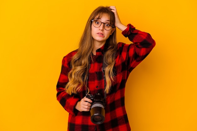 La giovane donna caucasica del fotografo isolata sulla parete gialla è scioccata, ha ricordato l'incontro importante.