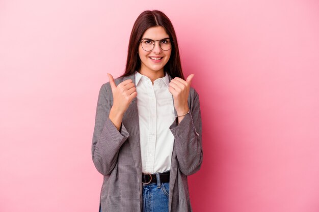 La giovane donna caucasica di affari isolata sulla parete rosa con i pollici aumenta, acclamazioni per qualcosa, concetto di rispetto e di sostegno