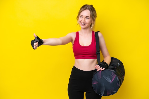 La giovane donna caucasica di sport con la borsa di sport ha isolato il fondo che dà un pollice in su gesto