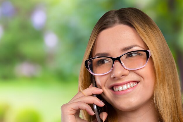 La giovane donna caucasica felice sta chiamando con un telefono cellulare