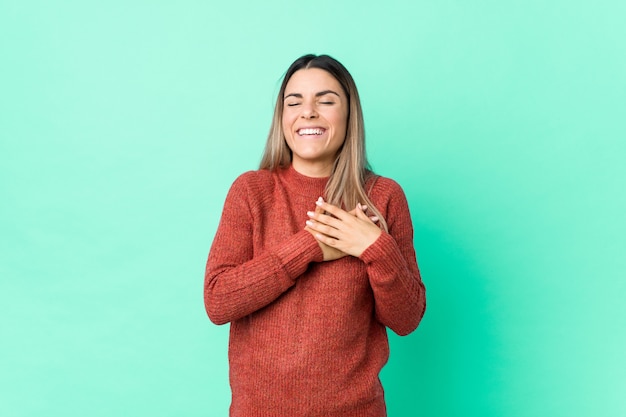 La giovane donna caucasica ha isolato la risata mantenendo le mani sul cuore, concetto di felicità.