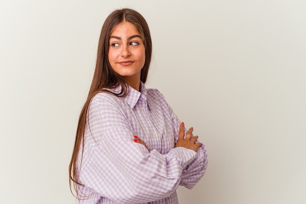 La giovane donna caucasica isolata su fondo bianco ride felicemente e si diverte a tenere le mani sullo stomaco.