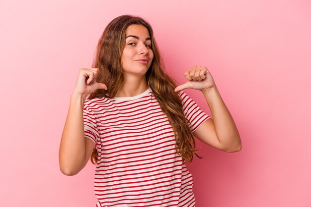 La giovane donna caucasica isolata su sfondo rosa si sente orgogliosa e sicura di sé, esempio da seguire.