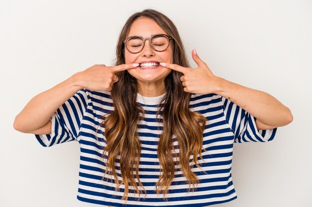 La giovane donna caucasica isolata sui sorrisi bianchi del fondo, indicando le dita alla bocca.