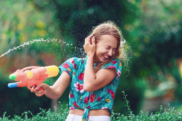 La giovane donna caucasica lotta con la pistola ad acqua al festival di Songkran. Concetto di vacanza/ Capodanno tailandese