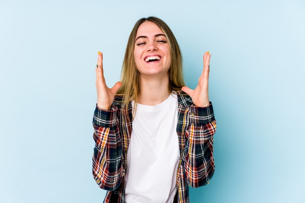 La giovane donna caucasica ride ad alta voce tenendo la mano sul petto.