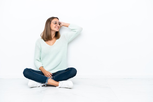 La giovane donna caucasica seduta sul pavimento isolato su sfondo bianco ha realizzato qualcosa e intendeva la soluzione