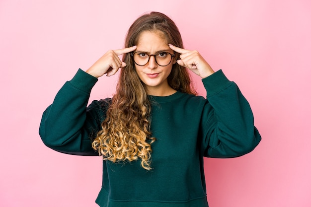 La giovane donna caucasica si è concentrata su un compito, mantenendo gli indici che puntano la testa.