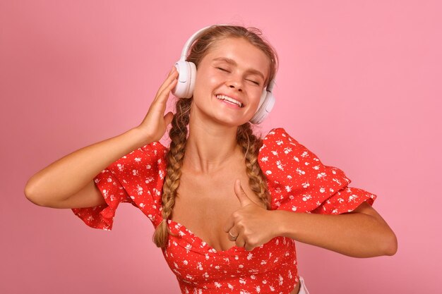 La giovane donna caucasica simpatica positiva ascolta la musica tramite le cuffie