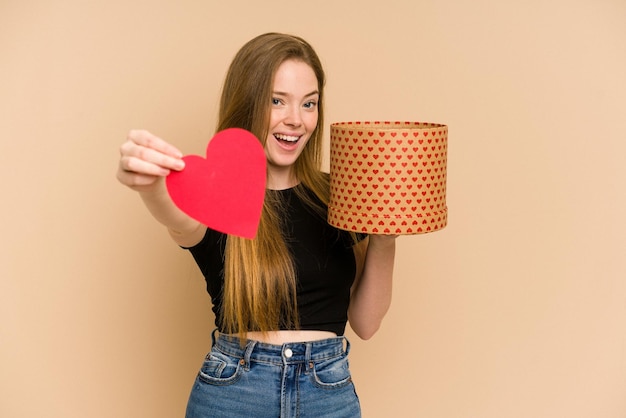 La giovane donna caucasica sorridente detiene il dono del cuore di San Valentino e una scatola.