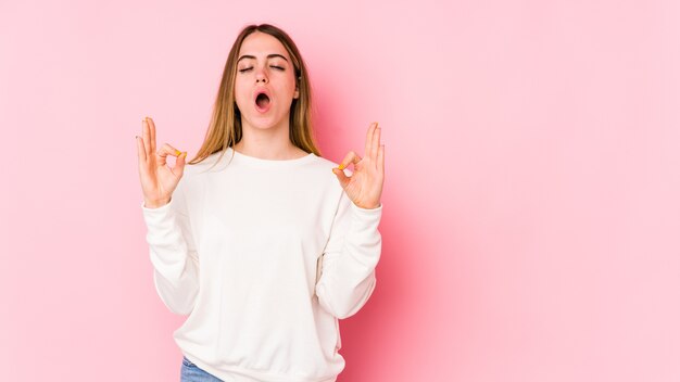 La giovane donna caucasica sulla parete rosa si rilassa dopo una dura giornata di lavoro