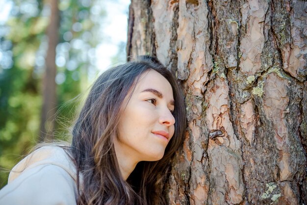 La giovane donna che abbraccia un grande albero ama il concetto della natura