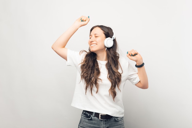 La giovane donna che balla sta ascoltando la musica su sfondo bianco.