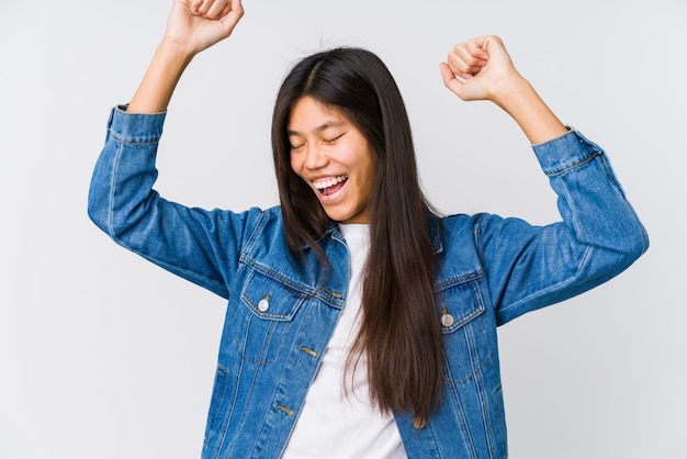 La giovane donna che celebra un giorno speciale, salta e alza le braccia con energia.