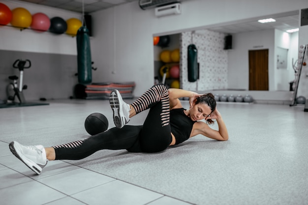 La giovane donna che fa la bicicletta sgranocchia in palestra.