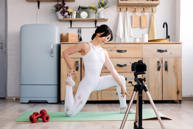 La giovane donna che pratica lo yoga e prende un video con la sua macchina fotografica