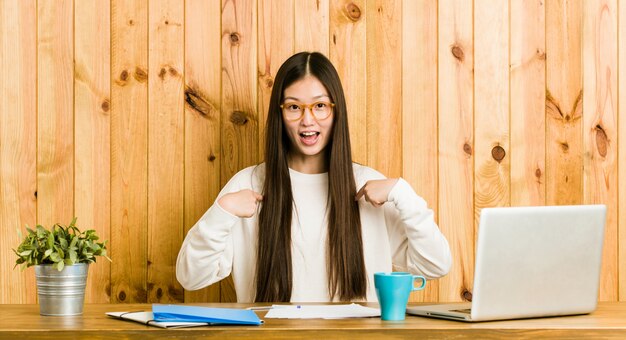 La giovane donna che studia sulla sua scrivania ha sorpreso indicare con il dito, sorridendo ampiamente