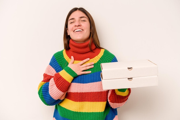 La giovane donna che tiene le pizze isolate su fondo bianco ride ad alta voce tenendo la mano sul petto