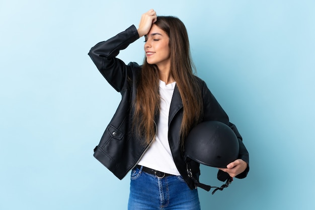 La giovane donna che tiene un casco del motociclo isolato sulla parete blu ha realizzato qualcosa e intende la soluzione