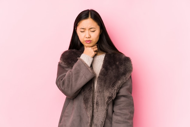 La giovane donna cinese che indossa un cappotto isolato soffre di dolore alla gola a causa di un virus o di un'infezione.