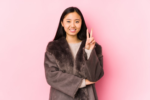 La giovane donna cinese che porta un cappotto ha isolato la mostra del numero due con le dita.