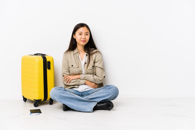 La giovane donna cinese del viaggiatore che si siede tenendo i passaggi di un imbarco che ride e che si diverte.