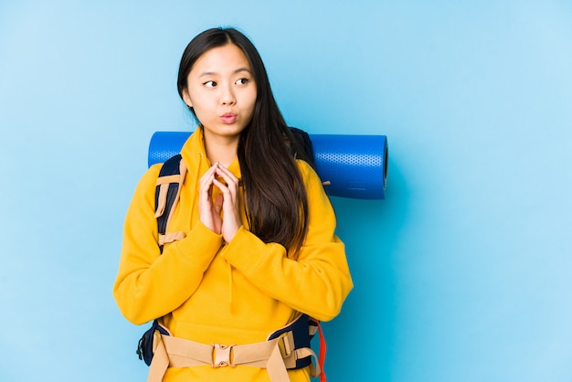 La giovane donna cinese di viaggiatore con zaino e sacco a pelo ha isolato il piano di fabbricazione in mente, installante un'idea.