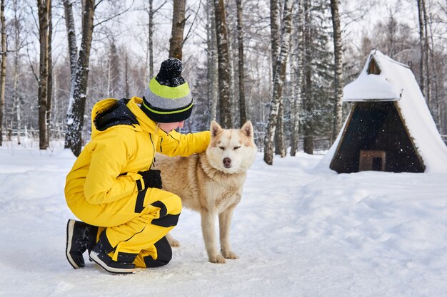 La giovane donna comunica con un cane husky nella foresta invernale