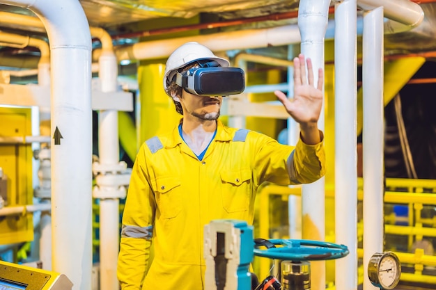 La giovane donna con gli occhiali e il casco gialli dell'uniforme da lavoro utilizza occhiali per realtà virtuale nell'industria