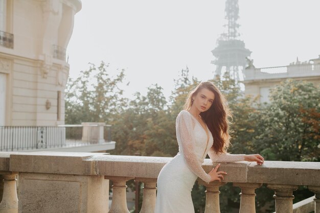 La giovane donna con i capelli scuri è in piedi davanti alla Torre Eiffel