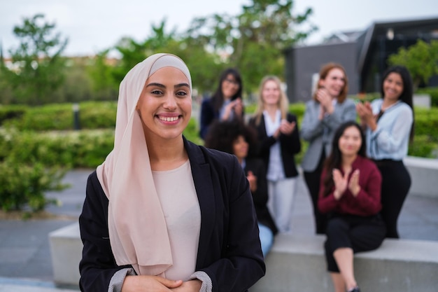 La giovane donna con l'hijab sorride applaudita dai suoi colleghi