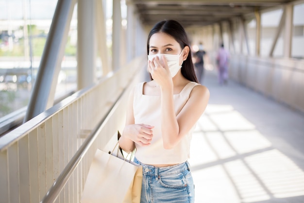 La giovane donna con la maschera di protezione sta stando la città all'aperto