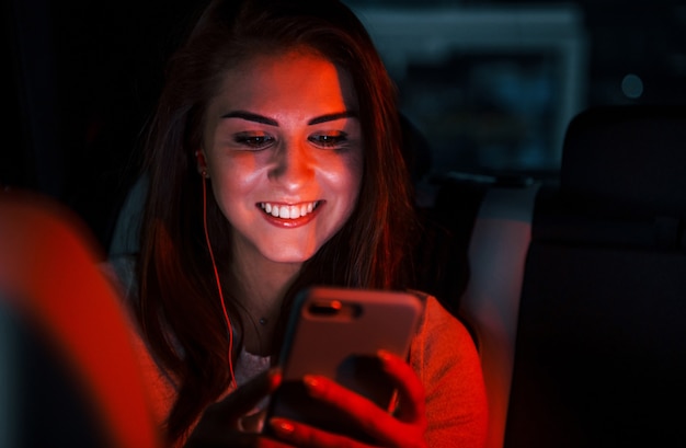 La giovane donna con lo smartphone è all'interno della nuovissima automobile moderna.
