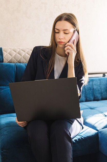 La giovane donna con un taccuino sta studiando o lavorando a casa e sta chiamando al telefono