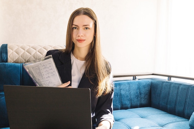 La giovane donna con un taccuino sta studiando o lavorando a casa e sta lavorando con un rapporto di marketing